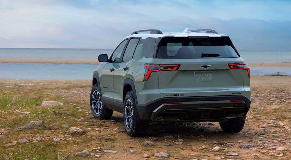 Rear view of a green 2025 Chevy Equinox ACTIV parked on a beach.