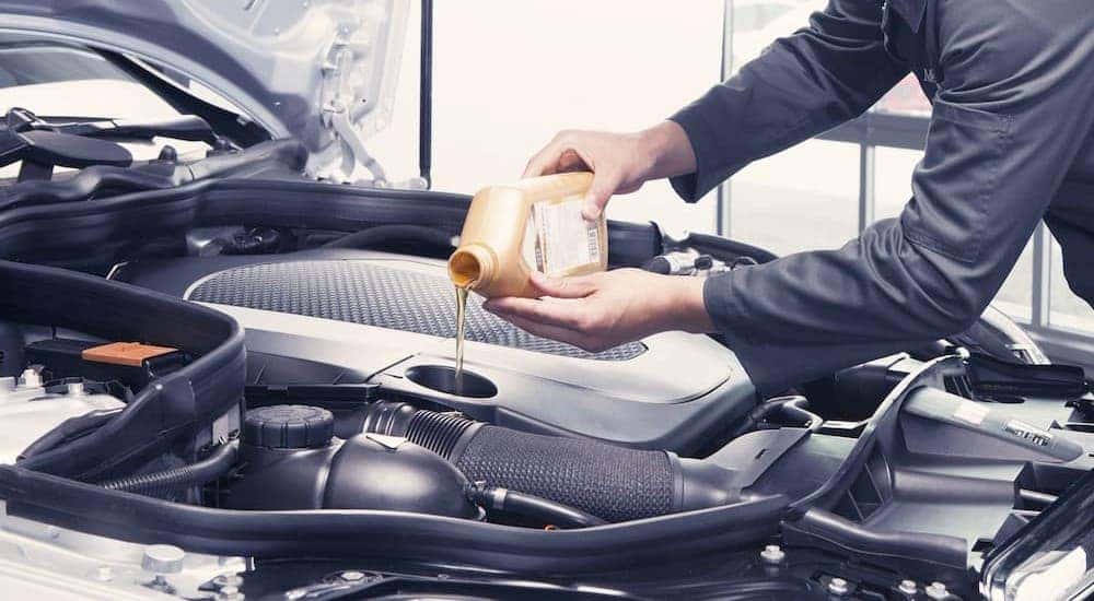 A technician is shown pouring oil into an engine.