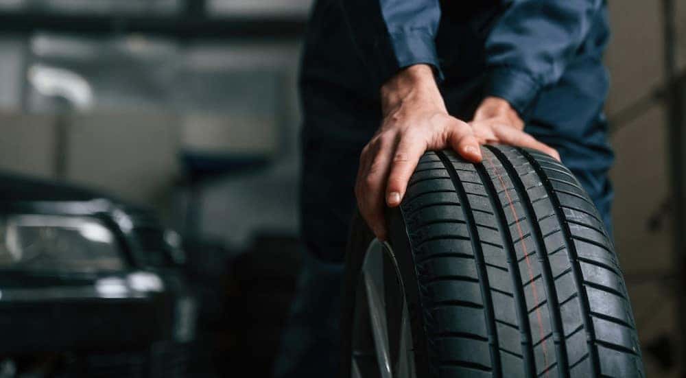 A technician is shown holding a tire.