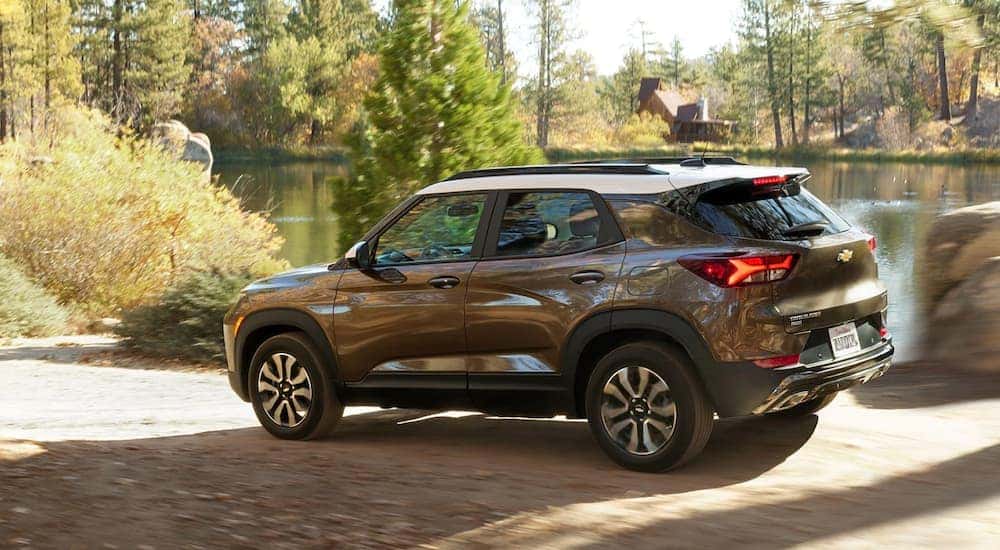 A brown 2021 Chevy Trailblazer ACTIV driving on a dirt road past a lake.