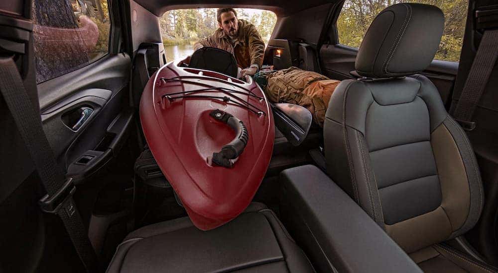 A man loading a kayak into the cargo area of a 2021 used Chevy Trailblazer for sale.
