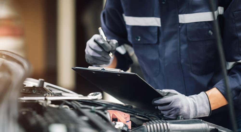 A technician is shown holding a clipboard and performing an inspection at a Honda service center.