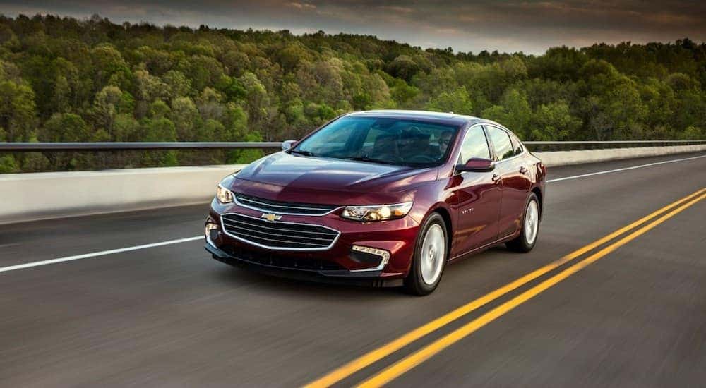 A maroon 2018 Chevy Malibu is shown driving on a highway.