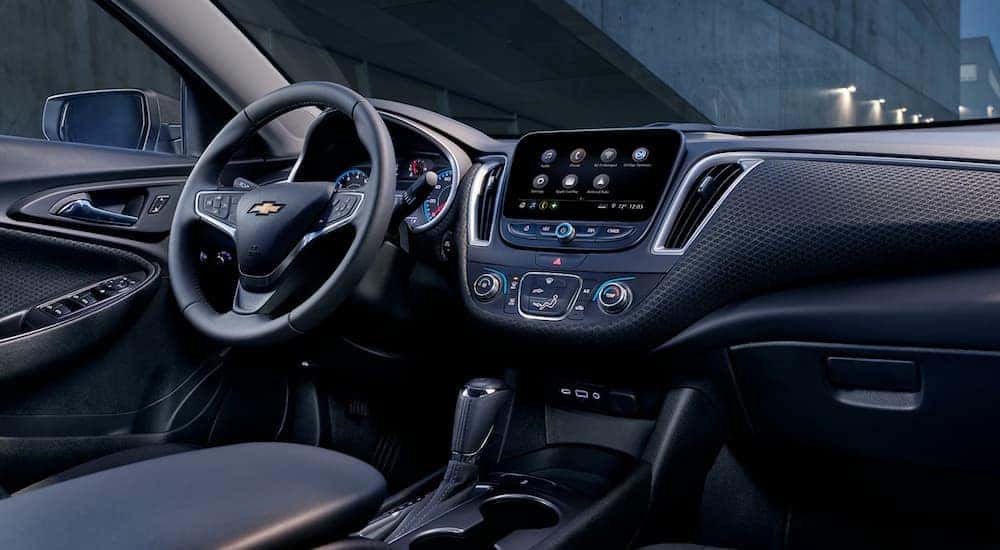 The black interior of a 2019 Chevy Malibu is shown from the passenger side.