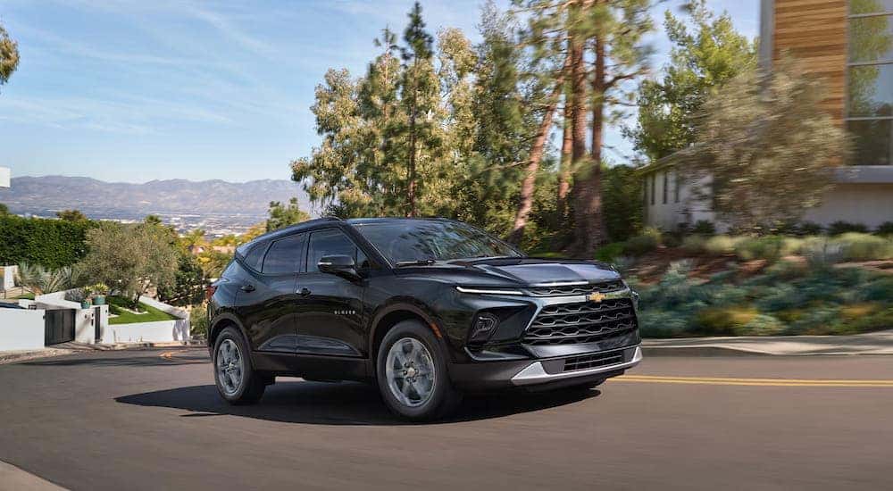 A black 2025 Chevy Blazer driving through a neighborhood.