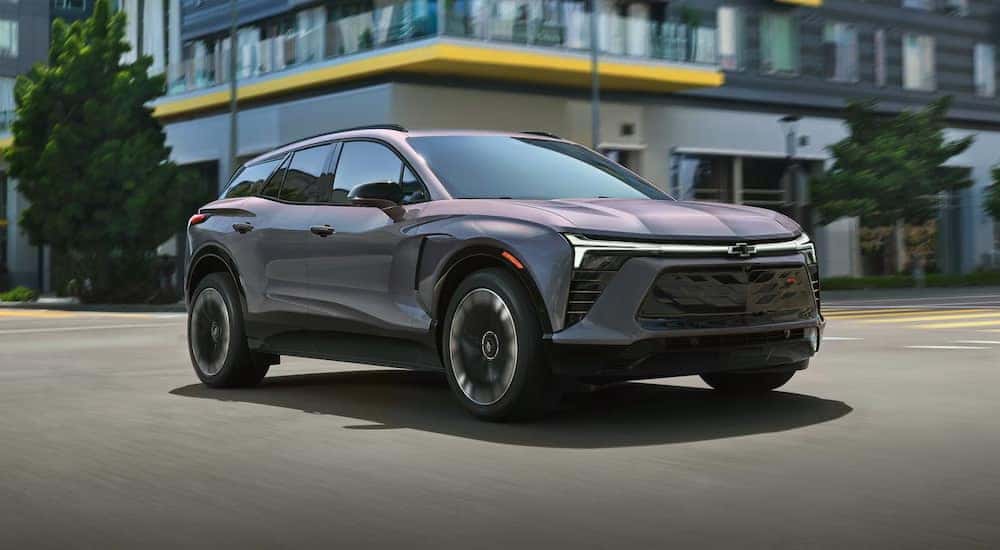 A grey 2025 Chevy Blazer EV driving through a city.