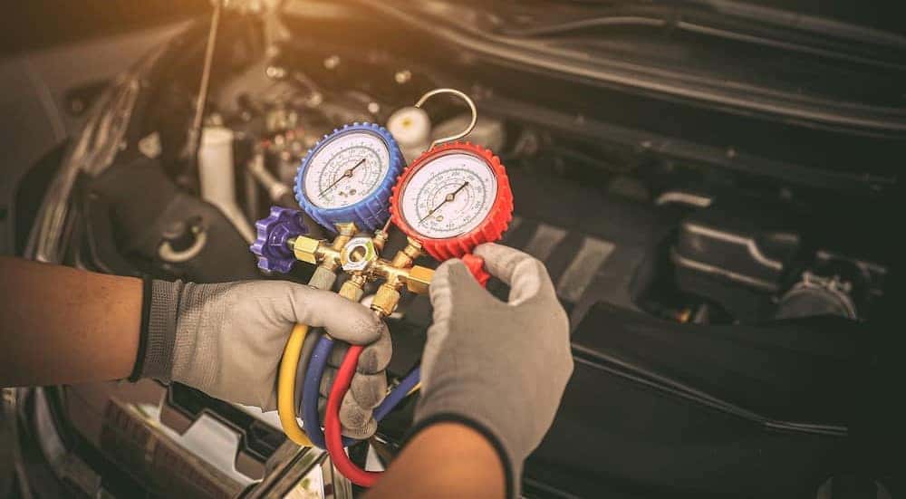 A technician is shown holding a meter to inspect the engine cooling system.