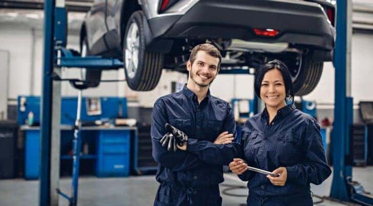 Two technicians are shown smiling at a Ford service center in Cincinnati.