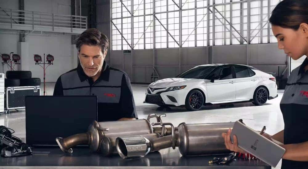 A white 2023 Toyota Camry TRD is shown in a warehouse.