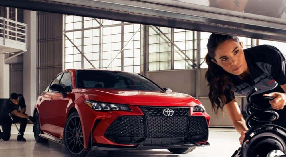 A red 2023 Toyota Camry TRD is shown in a warehouse.