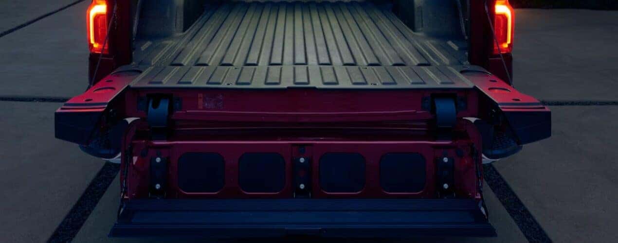A close-up of the multi-flex tailgate is shown on a red 2025 Chevy Silverado 1500.