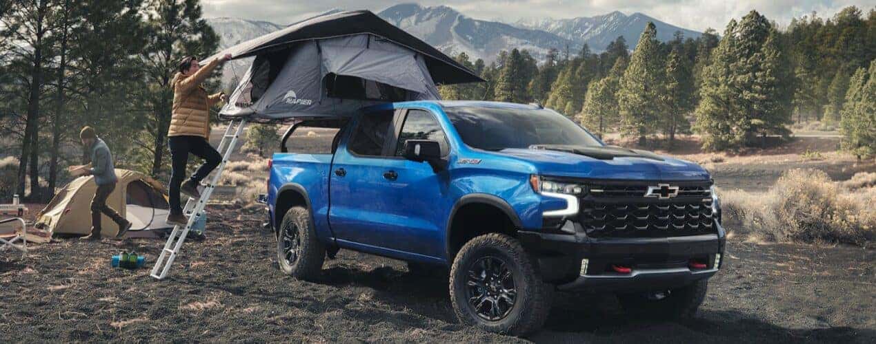 A blue 2025 Chevy Silverado 1500 ZR2 is shown parked on a camping site.