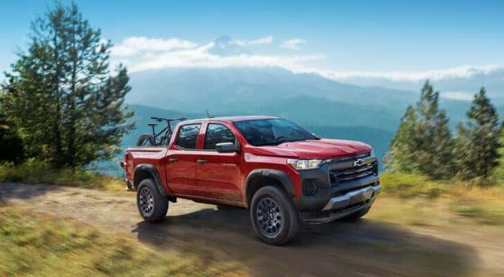 A red 2024 Chevy Colorado Trail Boss driving on a mountain trail.