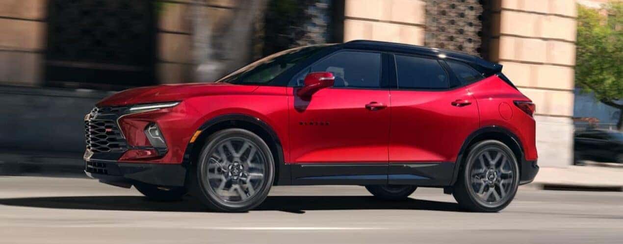 A red 2025 Chevy Blazer is shown driving on a city street.