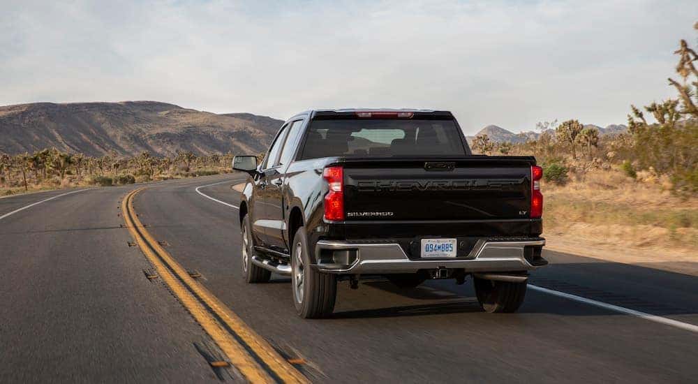 A black 2025 Chevy Silverado 1500 LT is shown from the rear at an angle.
