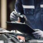 A technician is shown holding a clipboard before performing a commercial truck service.
