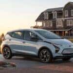 A white 2022 Chevy Bolt EV is shown driving to view used cars for sale near Florence.
