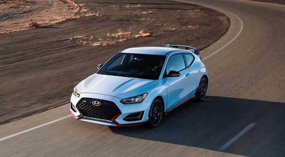 A white 2022 Hyundai Veloster N is shown driving on a highway.