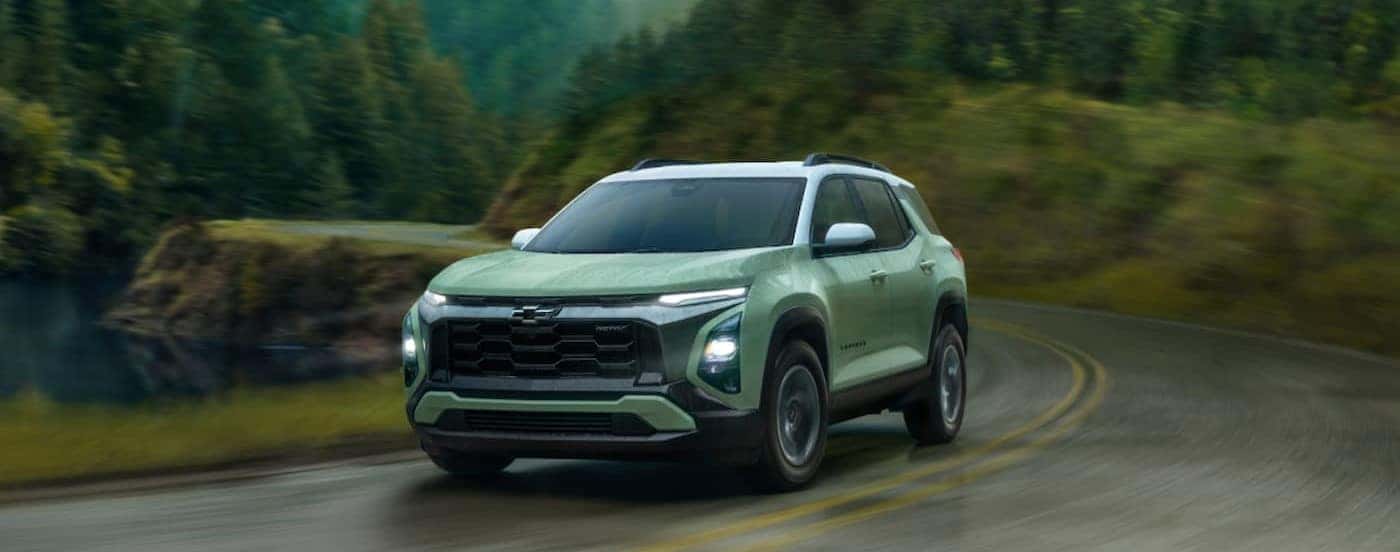 A green 2025 Chevy Equinox ACTIV is shown driving on a rainy day.