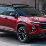 A red 2025 Chevy Equinox RS driving by a building from a dealer with a Chevy Equinox for sale in Cincinnati.