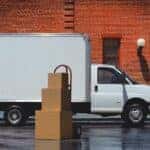 Side angle view of a white 2025 Chevy Express Cutaway parked by a building.