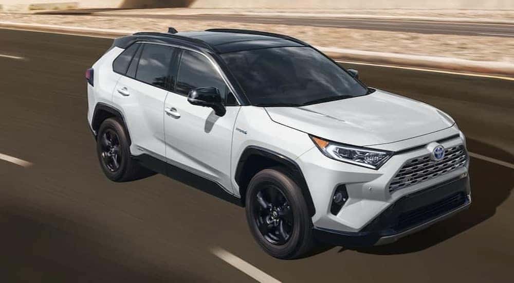 A white 2021 Toyota RAV4 driving on a highway.