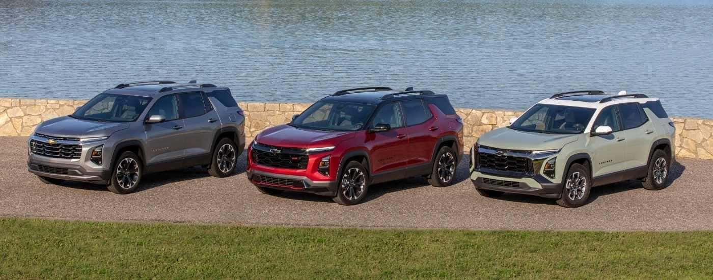 Three 2025 Chevy Equinox trims parked near water.