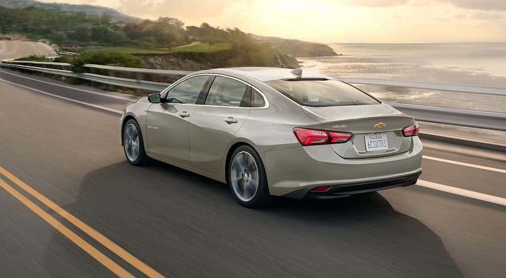 A tan 2025 Chevy Malibu driving on a highway.