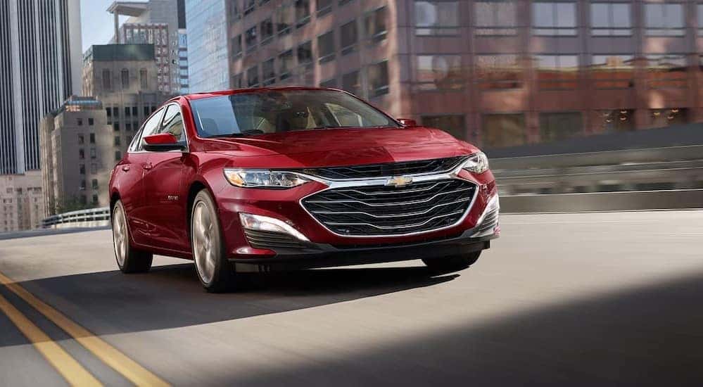 A red 2025 Chevy Malibu for sale in Cincinnati driving on a bridge.