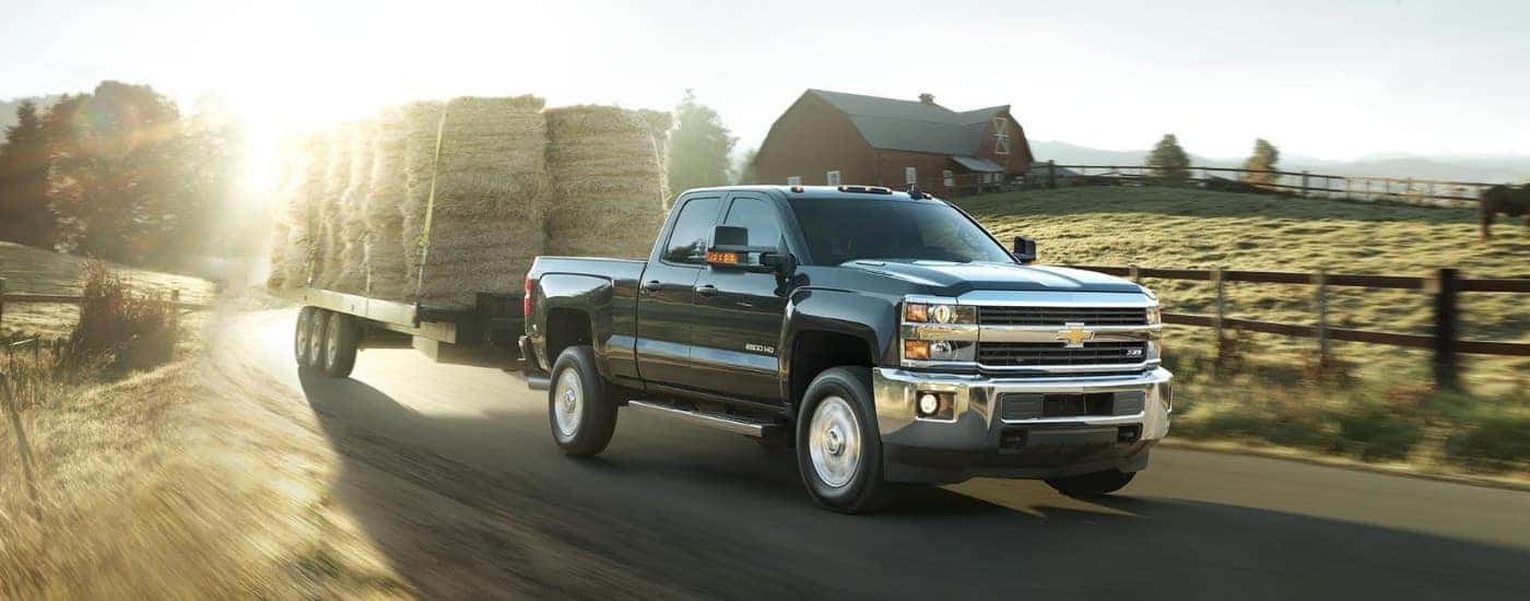 A black 2018 Chevy Silverado 2500 HD Z71 is towing hay bales.