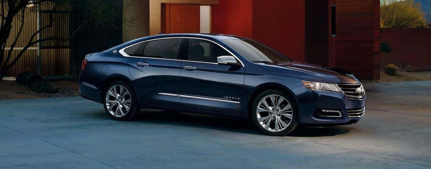 A blue 2020 Chevy Impala parked near a house.