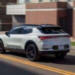 A white 2025 Chevy Equinox EV RS driving in a city.