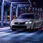 A silver 2025 Honda Civic Sport parked at night.