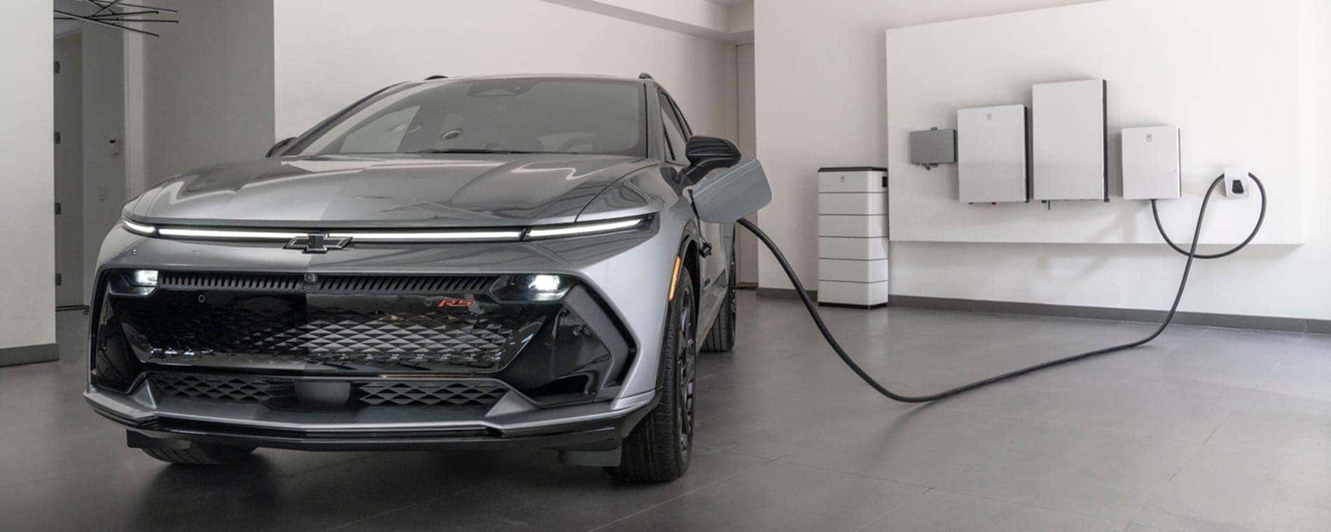 A grey 2025 Chevy Equinox EV RS charging in a garage.