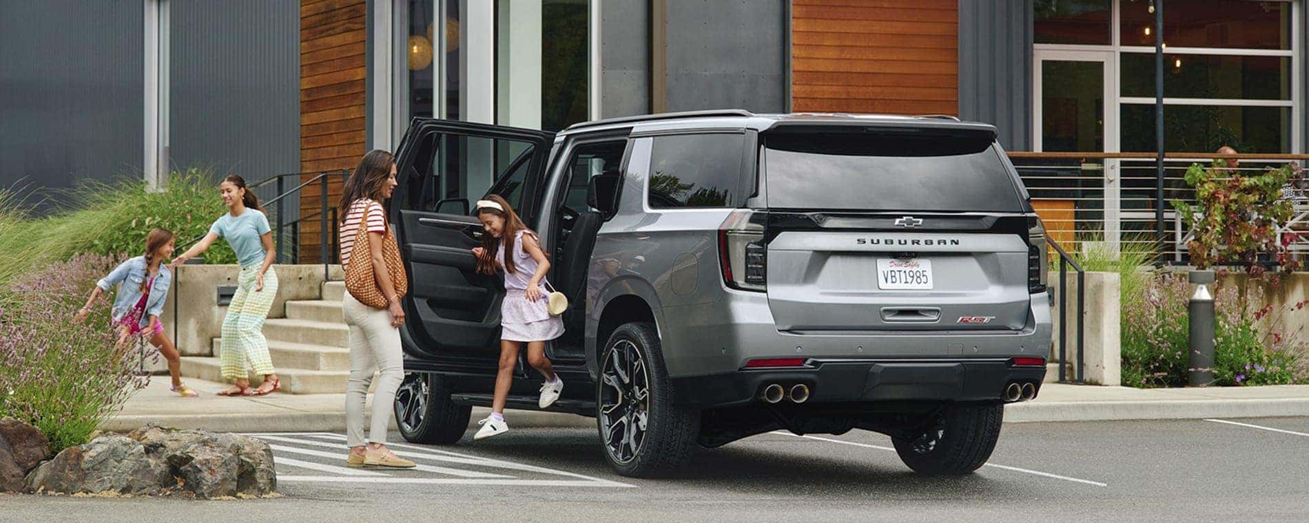 A family exiting a grey 2025 Chevy Suburban RST.