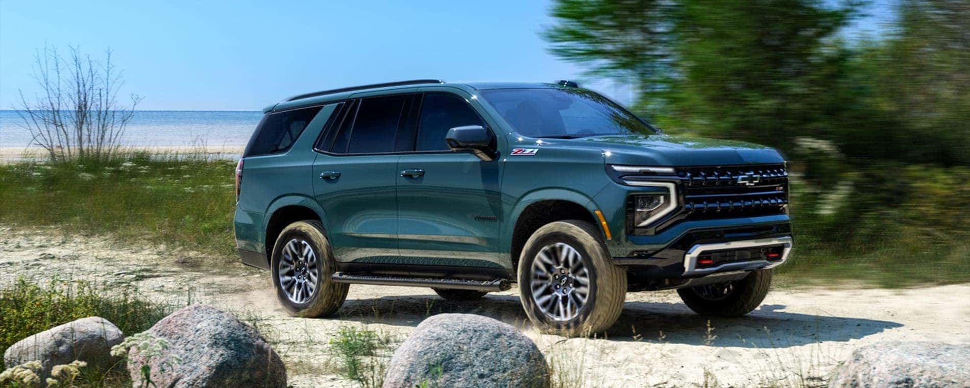 A green 2025 Chevy Tahoe Z71 driving on a trail.