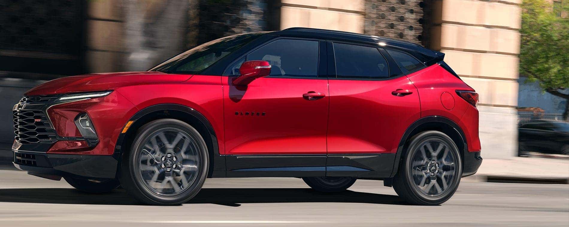 A red 2025 Chevy Blazer RS driving on a city street.