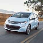 A light blue 2017 Chevy Bolt EV driving on a highway.