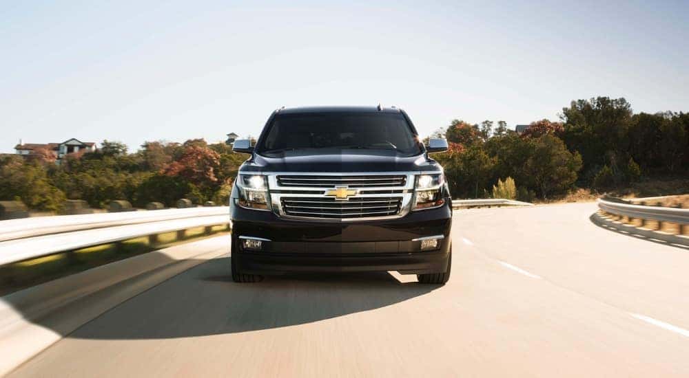 Black 2017 Chevy Suburban driving down a road.