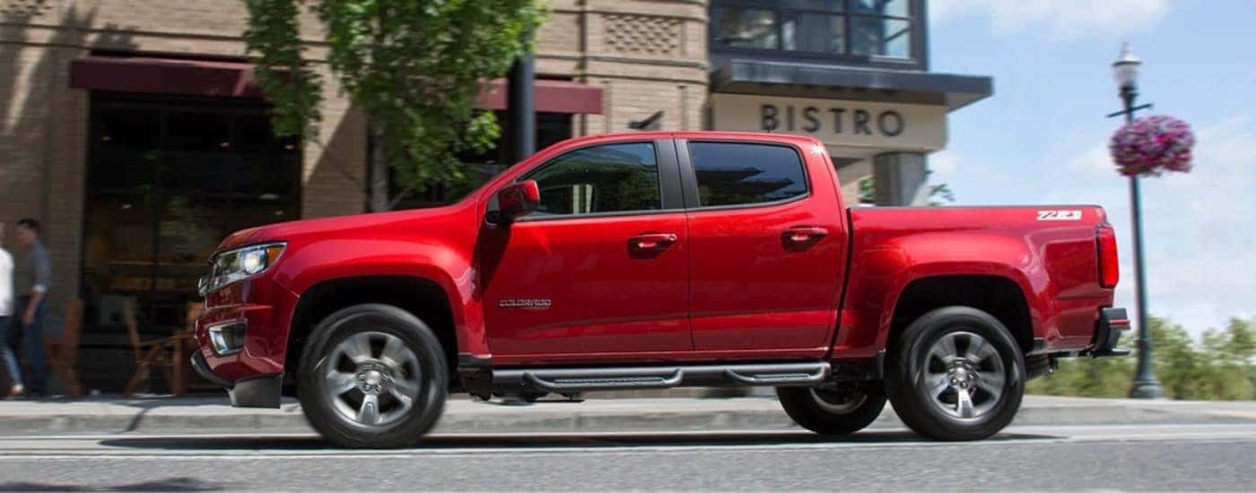 A red 2015 Chevy Colorado for sale in Cincinnati driving on a city street.