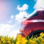 A red vehicle driving near flowers.