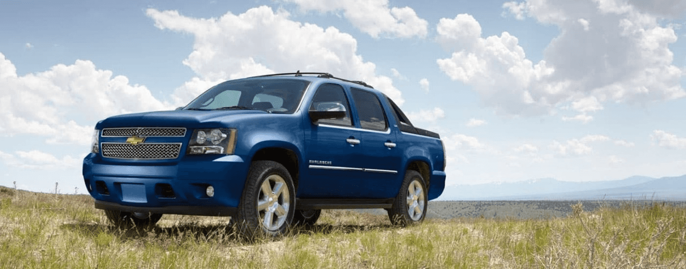 A blue 2012 Chevy Avalanche parked on a field.