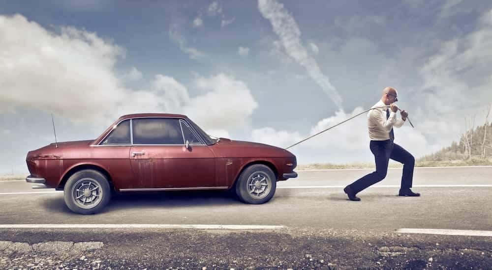 A man is shown pulling a car.