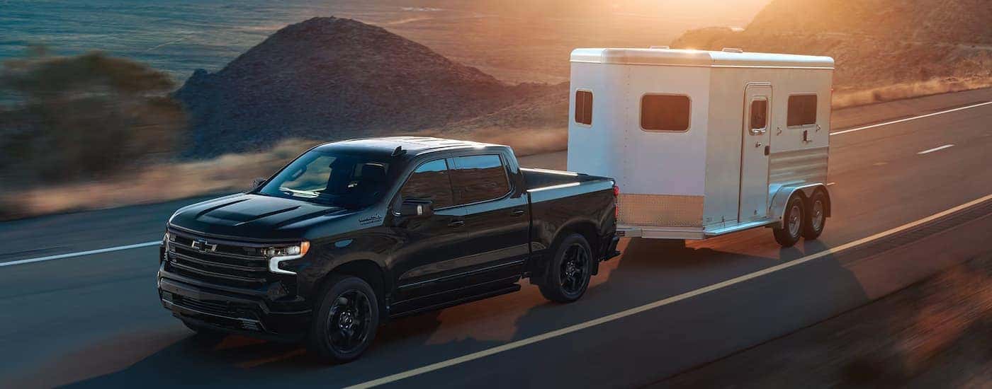 A black 2025 Chevy Silverado 2500 towing a trailer