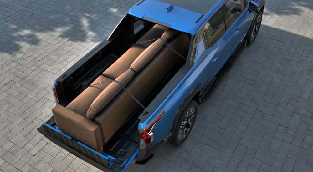A couch stored in the bed of a blue 2025 Chevy Silverado EV.