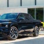 A black 2025 Chevy Silverado EV RST charging at a charge station.