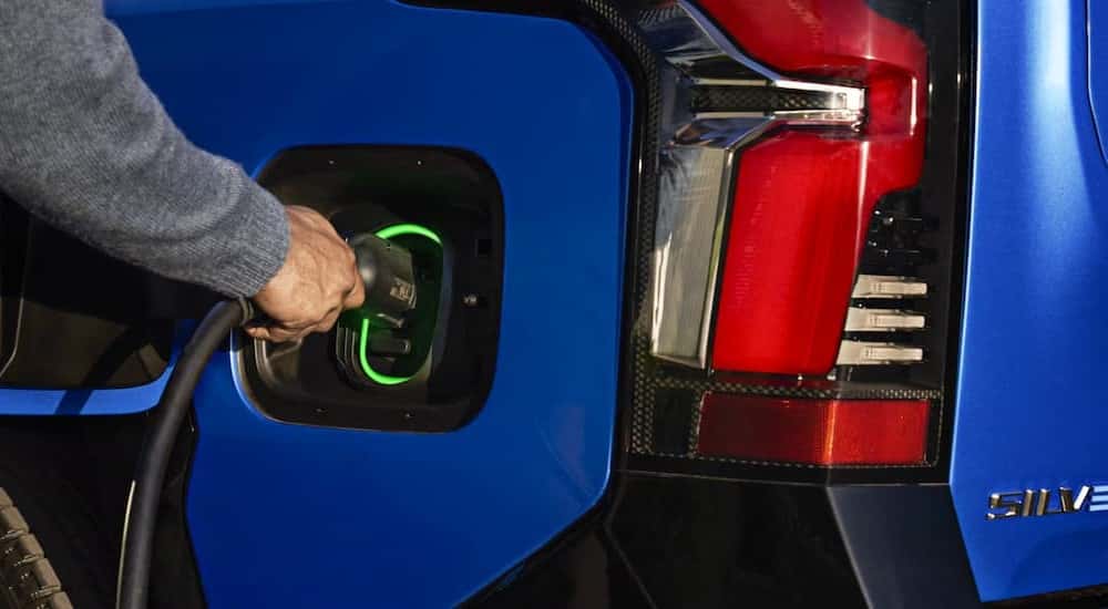 Close-up of a person charging a blue 2025 Chevy Silverado EV.