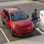 A red 2023 Chevy Bolt EUV parked near a charge station.