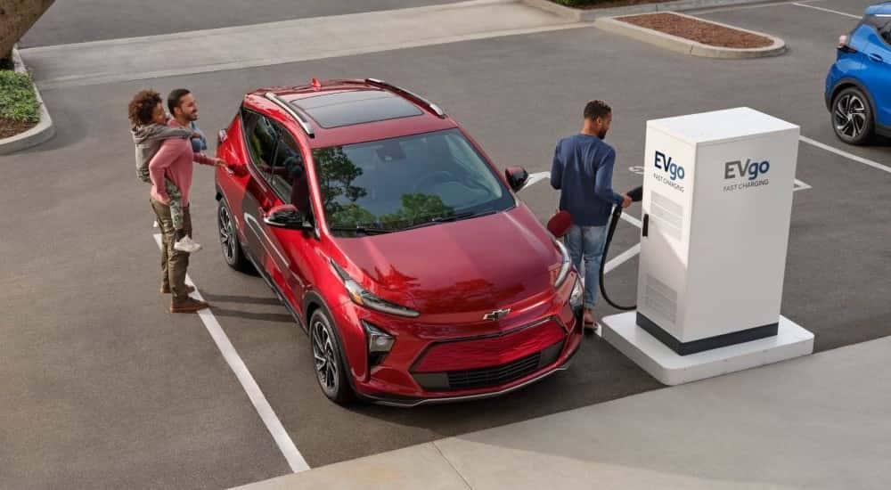 A red 2023 Chevy Bolt EUV parked near a charge station.