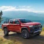 A red 2025 Chevy Colorado Trail Boss driving on a dirt path.